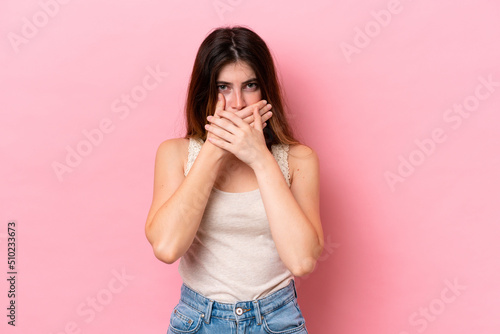 Young caucasian woman isolated on pink background covering mouth with hands