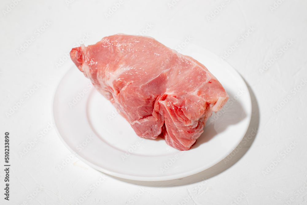 Raw meat on a plate. White background. Piece of fresh pork meat. Raw meat on a plate. White background. Piece of fresh pork meat.