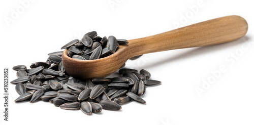 Wooden spoon and unpeeled sunflower seeds on white background