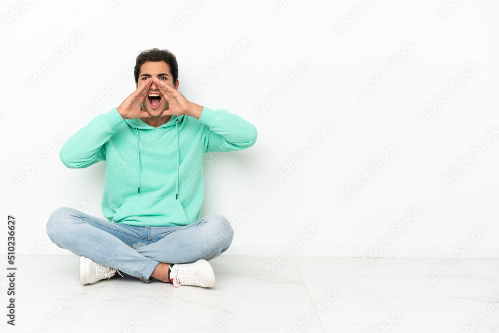 Caucasian handsome man sitting on the floor shouting and announcing something Caucasian handsome man sitting on the floor shouting and announcing something