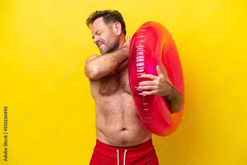 Middle age caucasian man holding inflatable donut isolated on yellow background suffering from pain in shoulder for having made an effort Middle age caucasian man holding inflatable donut isolated on yellow background suffering from pain in shoulder for having made an effort