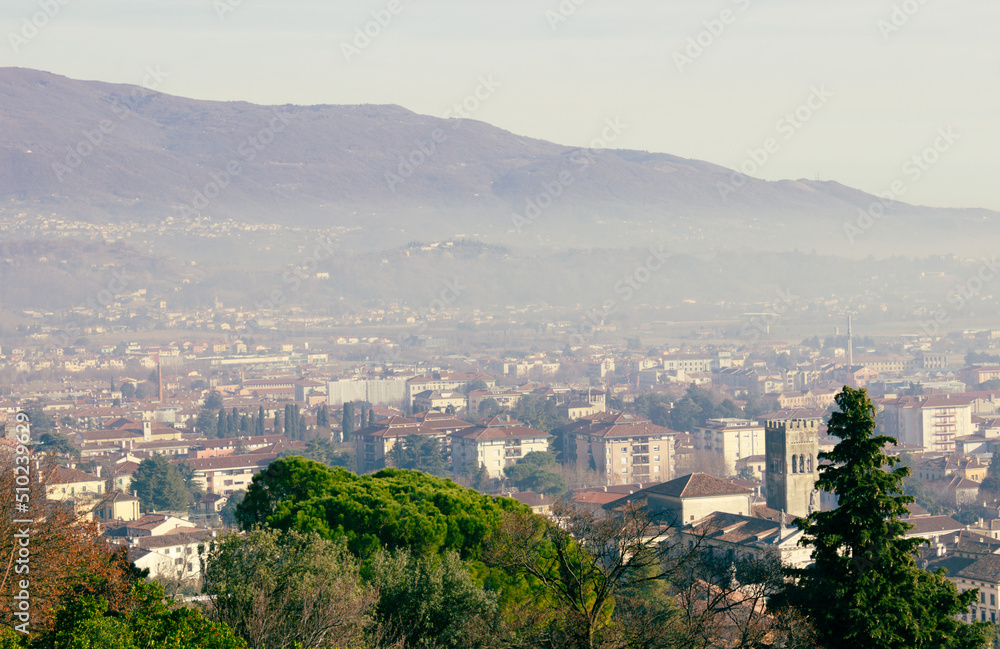 Urban landscape. Aerial view of the city of Vittorio Veneto with the mountains in the background. Day with haze.