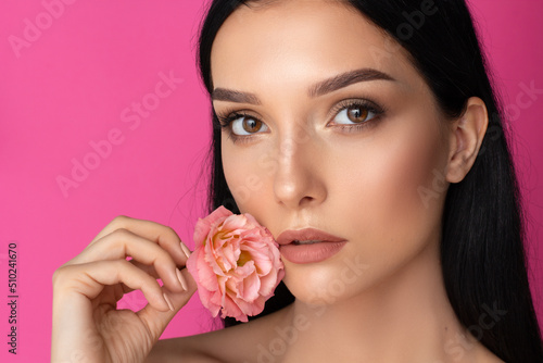 a beauty brunette woman portrait a pink flower in the hand