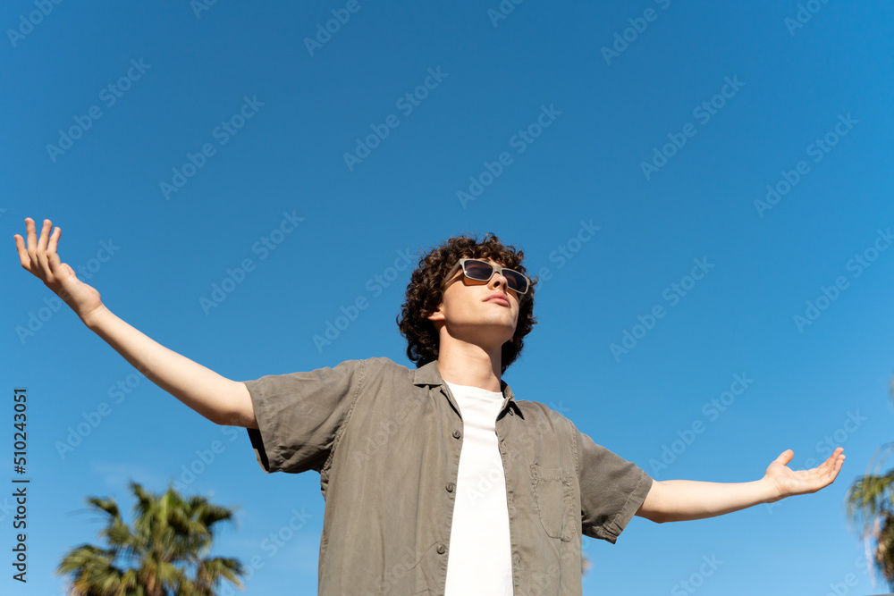 Man wearing sunglasses standing with spread arms while walking outdoors and enjoying the nature Man wearing sunglasses standing with spread arms while walking outdoors and enjoying the nature