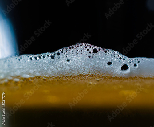 Obraz na płótnie A closeup of dark beer in a cup with bubble suds at the top, foam formed on top of a alcoholic beverage. w salonie