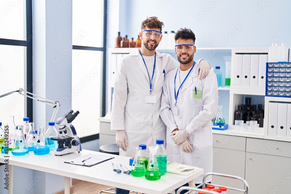 Young couple wearing scientist uniform hugging each other at laboratory Young couple wearing scientist uniform hugging each other at laboratory