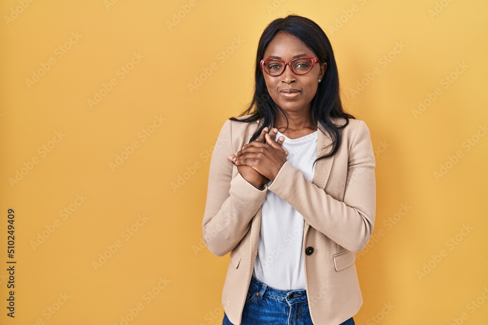 African young woman wearing glasses smiling with hands on chest with closed eyes and grateful gesture on face. health concept.