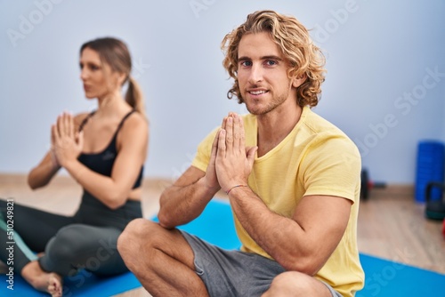 Man and woman couple smiling confident training yoga at sport center