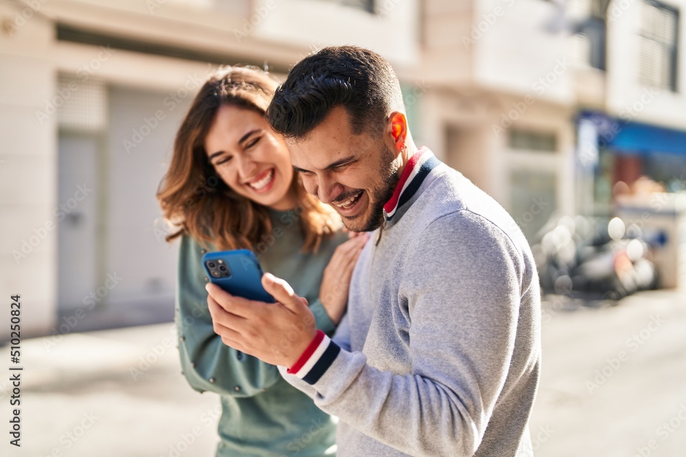 Man and woman smiling confident using smartphone at street Man and woman smiling confident using smartphone at street