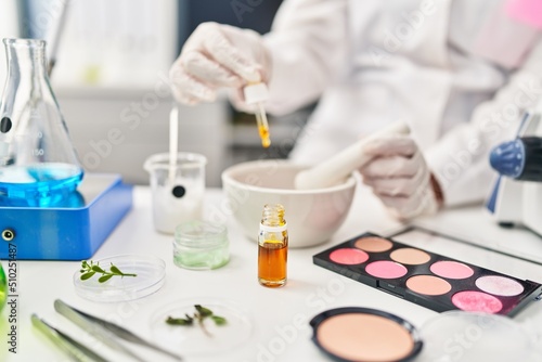 Foto Young hispanic woman scientist making makeup working at laboratory