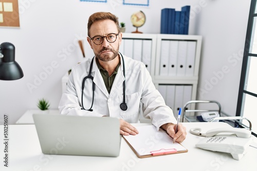 Middle age hispanic man wearing doctor uniform working at clinic