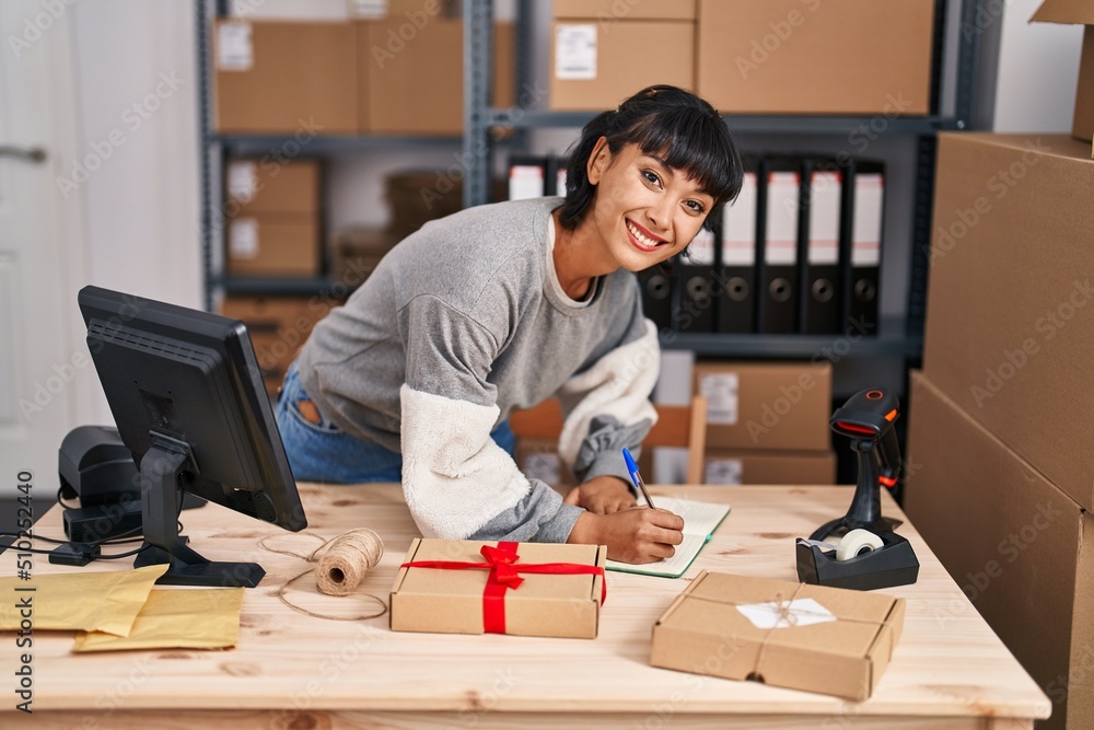 Young woman ecommerce business worker writing on book working at office Young woman ecommerce business worker writing on book working at office