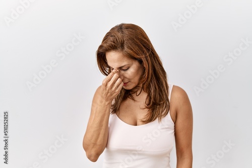 Middle age hispanic woman standing over isolated background tired rubbing nose and eyes feeling fatigue and headache. stress and frustration concept.