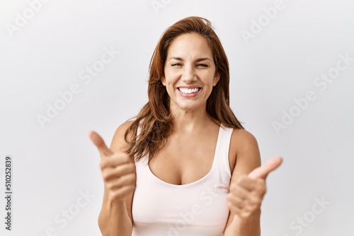Wallpaper Mural Middle age hispanic woman standing over isolated background success sign doing positive gesture with hand, thumbs up smiling and happy. cheerful expression and winner gesture. Torontodigital.ca