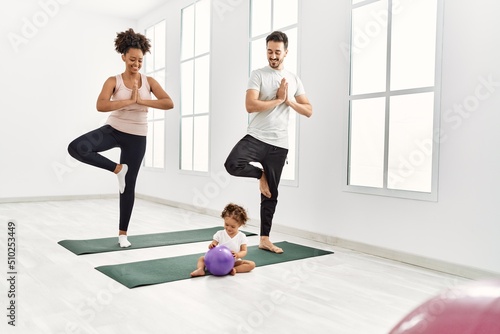 Couple and daughter smiling confident training yoga at sport center
