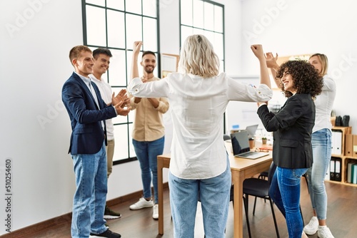 Group of young business workers smiling and clapping. Young businesswoman doing strong gesture with arms on back view at the office.