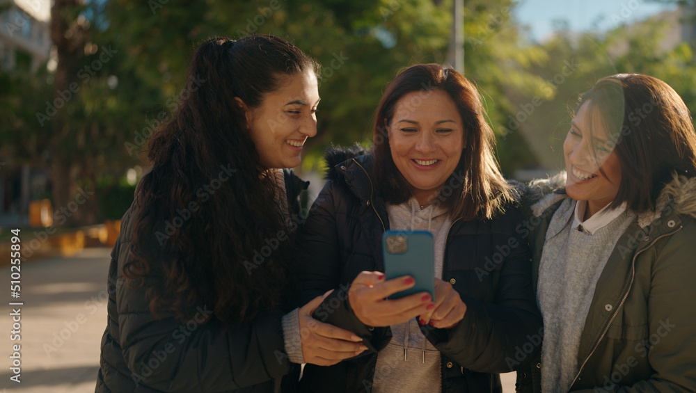 Mother and daugthers using smartphone standing together at park Mother and daugthers using smartphone standing together at park