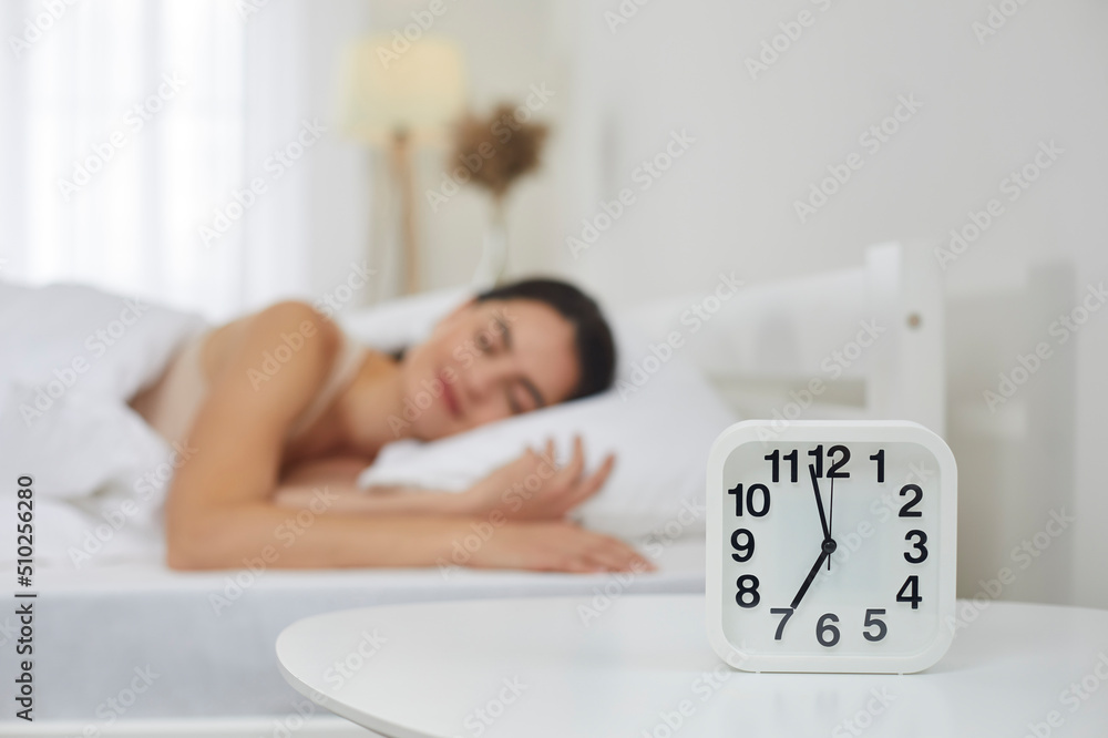 Foto de Close up of white plastic alarm clock set for 7 AM on bedside