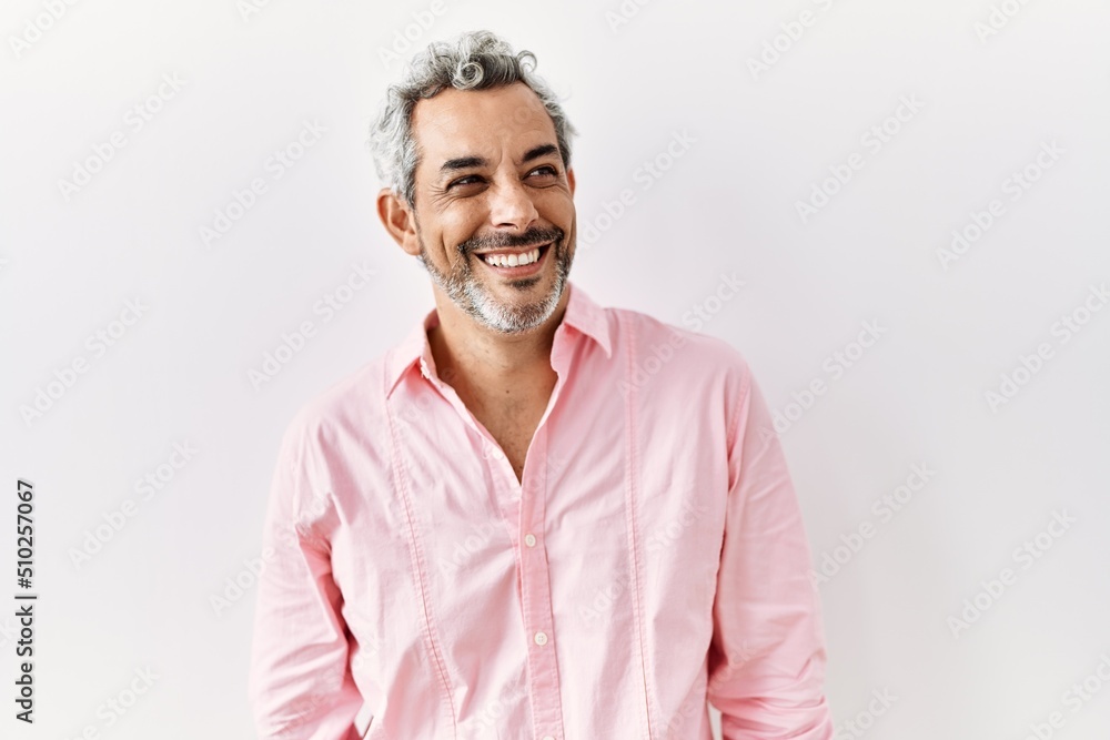 Middle age hispanic man standing over isolated background looking away to side with smile on face, natural expression. laughing confident. Middle age hispanic man standing over isolated background looking away to side with smile on face, natural expression. laughing confident.