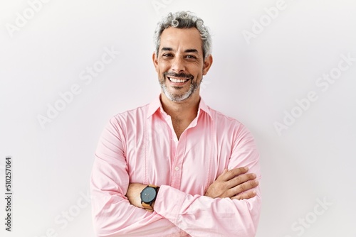 Middle age hispanic man standing over isolated background happy face smiling with crossed arms looking at the camera. positive person.