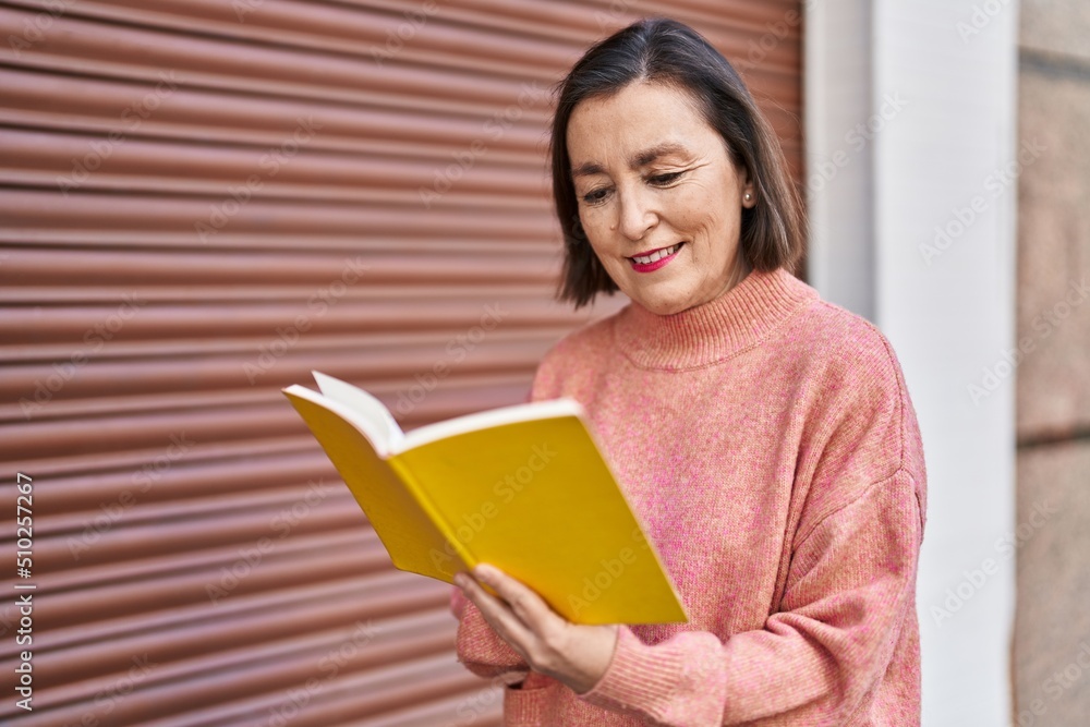 Middle age woman smiling confident reading book at street Middle age woman smiling confident reading book at street