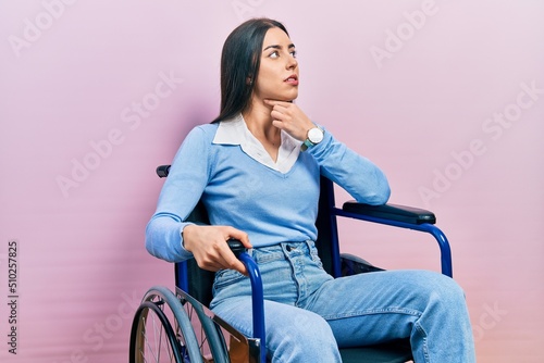 Beautiful woman with blue eyes sitting on wheelchair touching painful neck, sore throat for flu, clod and infection
