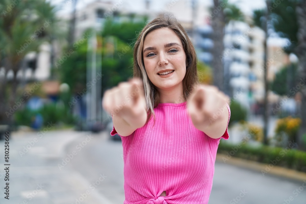 Young woman smiling confident pointing with fingers at street Young woman smiling confident pointing with fingers at street