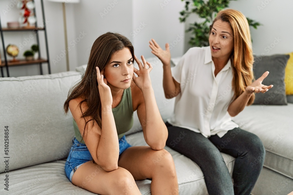 Mother and daughter unhappy arguing sitting on sofa at home Mother and daughter unhappy arguing sitting on sofa at home