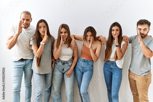 Fotografija Group of young friends standing together over isolated background hand on mouth