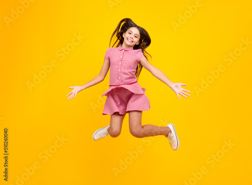 Fototapeta Naklejka Na Ścianę i Meble -  Full size length of young brunette girl teen student jump run go move hurry up isolated on yellow background studio.