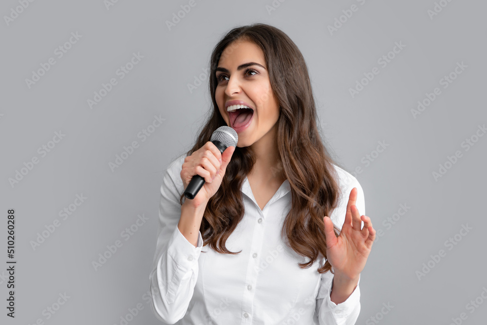 Young excited woman singing a song with a microphone, presenting an event or having a party. Happy singing girl. Young excited woman singing a song with a microphone, presenting an event or having a party. Happy singing girl.
