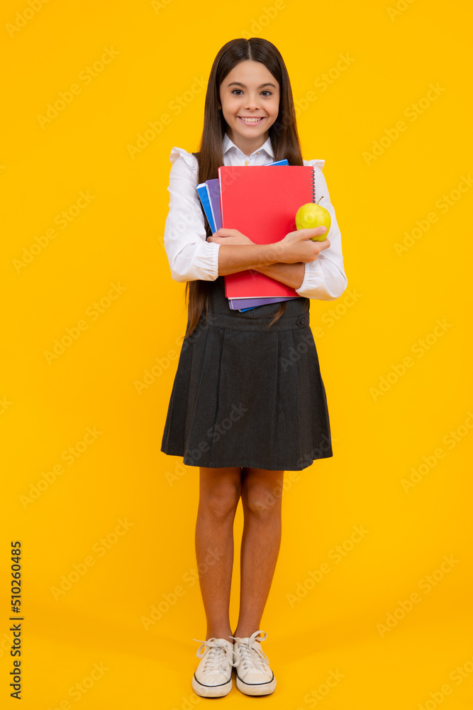 Back to school. Full length of teenager school girl with backpack hold aplle ready to learn. School children with school bag on isolated yellow studio background. Back to school. Full length of teenager school girl with backpack hold aplle ready to learn. School children with school bag on isolated yellow studio background.