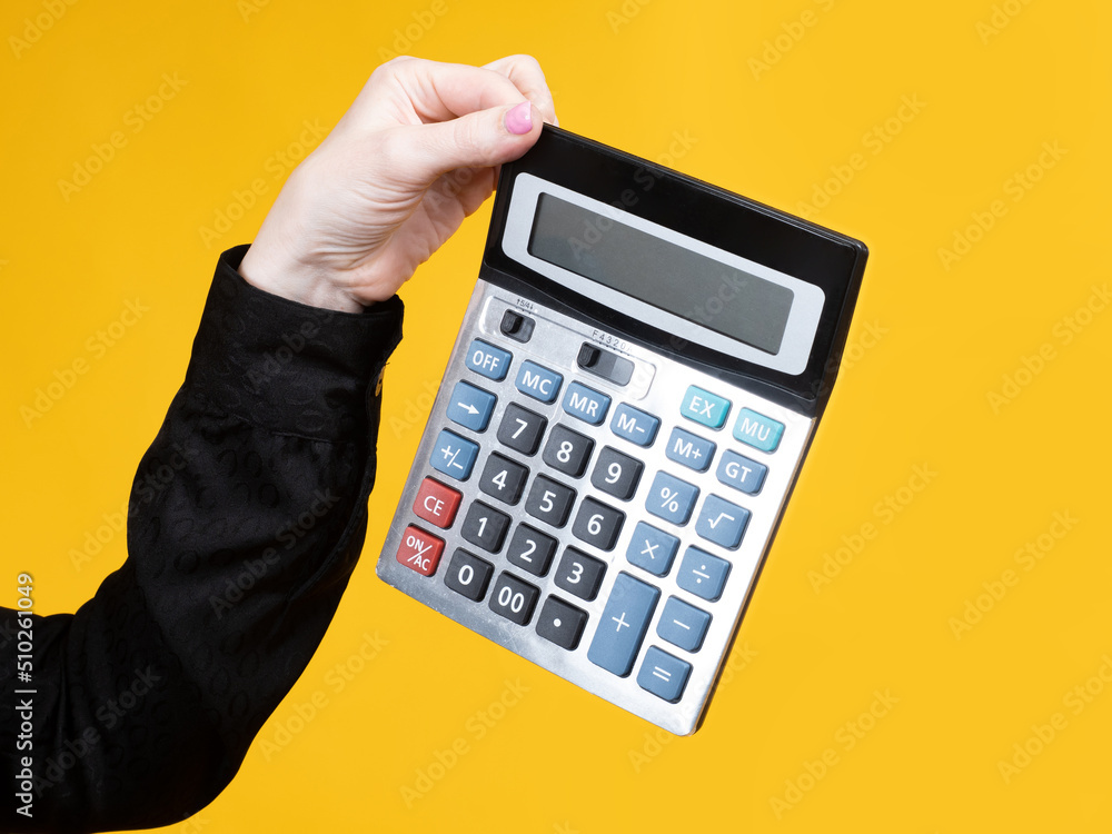 Calculator in hand. Turned off calculator. Concept of accounting and financial accounting. Accounting calculator on orange. Accountant services. Device for mathematical calculations Calculator in hand. Turned off calculator. Concept of accounting and financial accounting. Accounting calculator on orange. Accountant services. Device for mathematical calculations