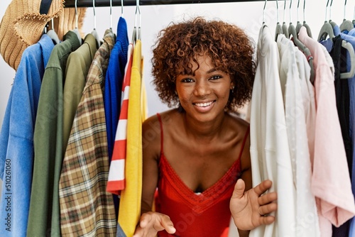 Stampa su tela Young african american woman smiling confident appearing through rack at clothin