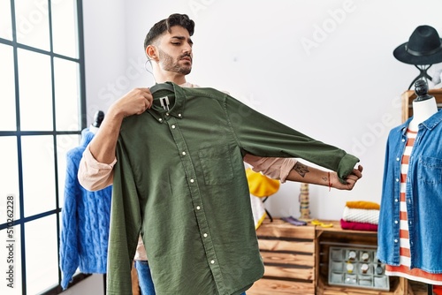 Bild auf Leinwand Handsome hispanic man shopping trying on a shirt at retail shop