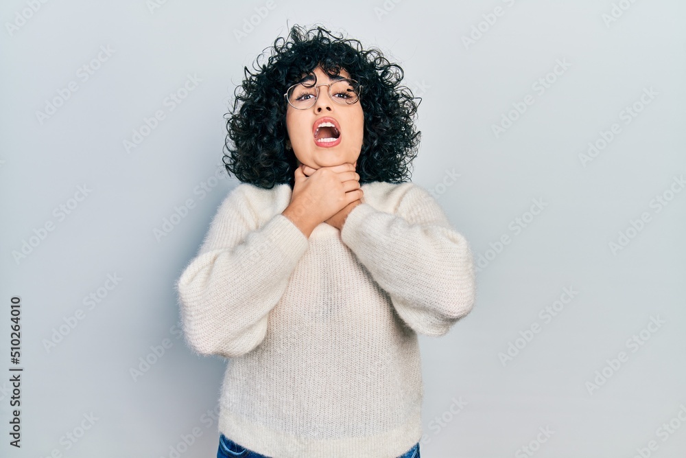 Young middle east woman wearing casual white tshirt shouting and suffocate because painful strangle. health problem. asphyxiate and suicide concept. Young middle east woman wearing casual white tshirt shouting and suffocate because painful strangle. health problem. asphyxiate and suicide concept.