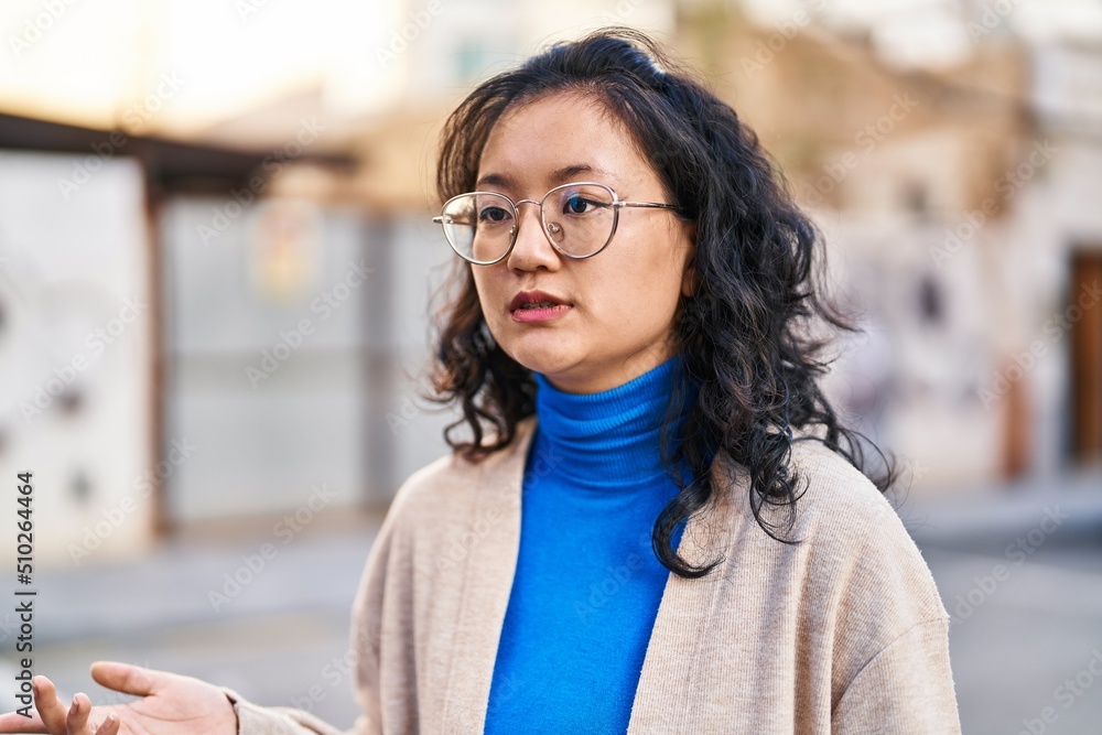 Young chinese woman with relaxed expression standing at street Young chinese woman with relaxed expression standing at street
