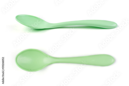 Children's plastic green spoon on a white isolated background in different angles. Dishes for the baby. Side view, top view.
