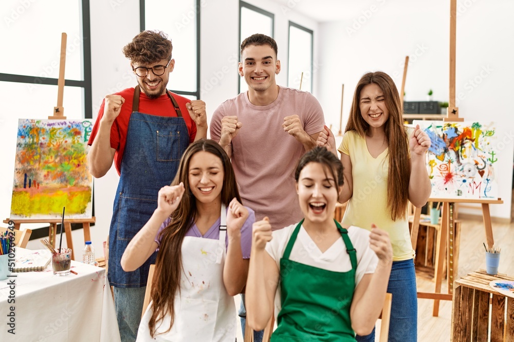 Group of five hispanic artists at art studio excited for success with arms raised and eyes closed celebrating victory smiling. winner concept. Group of five hispanic artists at art studio excited for success with arms raised and eyes closed celebrating victory smiling. winner concept.