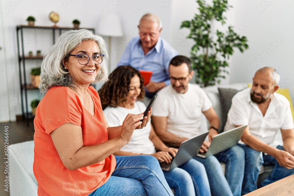 Group of middle age friends using laptop and smartphone sitting on the sofa at home. Group of middle age friends using laptop and smartphone sitting on the sofa at home.