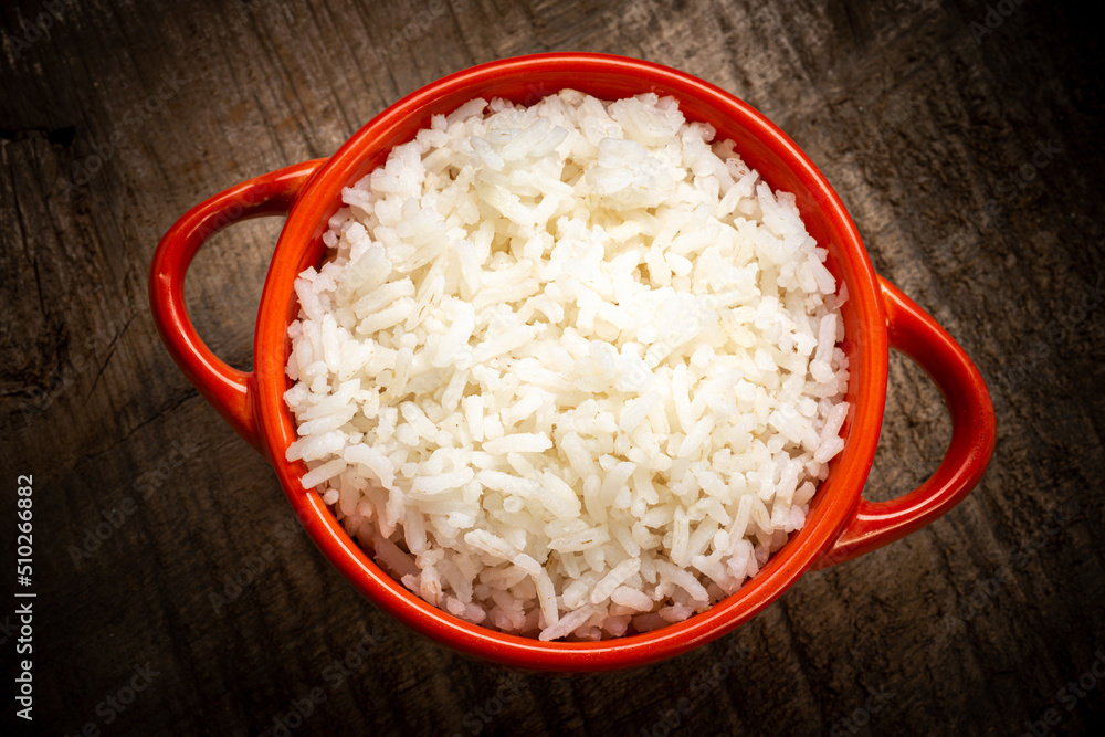 White rice served in a clay bowl on a rustic wooden table White rice served in a clay bowl on a rustic wooden table