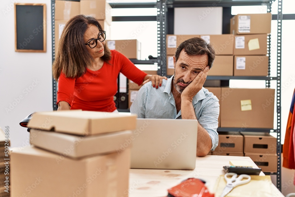 Middle age man and woman business partners stressed working at storehouse Middle age man and woman business partners stressed working at storehouse