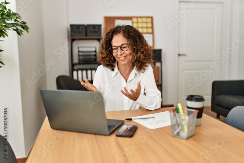 Middle age hispanic woman smiling confident having video call at office