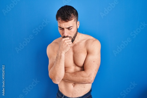 Handsome hispanic man standing shirtless feeling unwell and coughing as symptom for cold or bronchitis. health care concept.