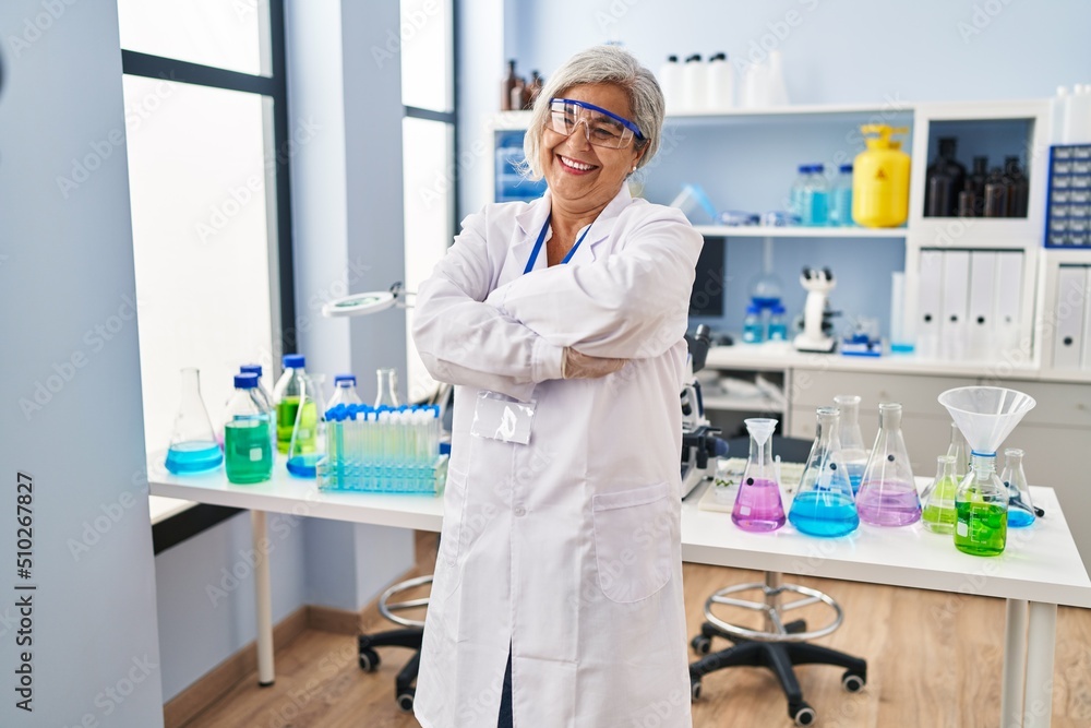 Middle age woman wearing scientist uniform standing with arms crossed gesture at laboratory Middle age woman wearing scientist uniform standing with arms crossed gesture at laboratory
