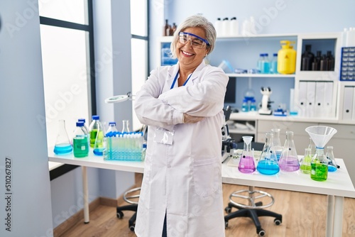 Fototapeta Naklejka Na Ścianę i Meble -  Middle age woman wearing scientist uniform standing with arms crossed gesture at laboratory