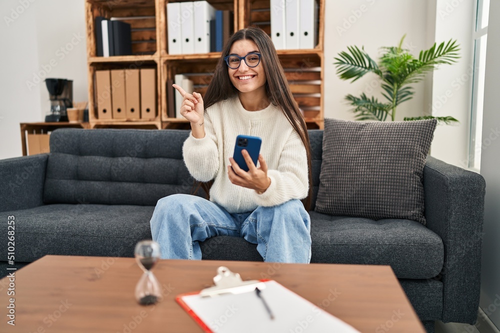 Young hispanic woman going to therapy at consultation office smiling happy pointing with hand and finger to the side Young hispanic woman going to therapy at consultation office smiling happy pointing with hand and finger to the side