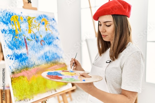 Fotografía Young hispanic artist woman wearing french beret drawing at art studio