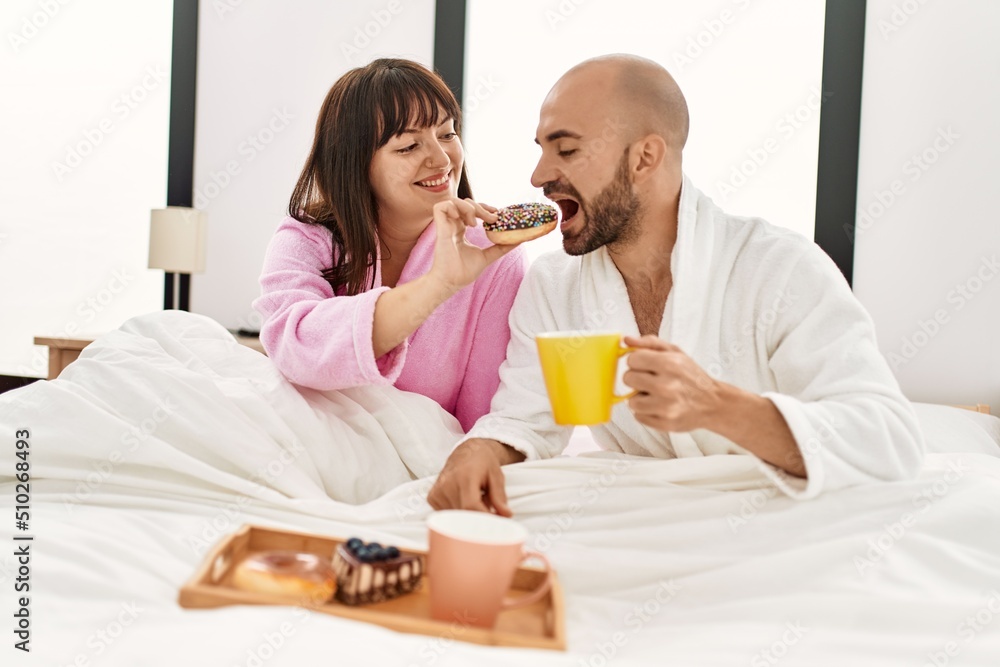 Young hispanic couple having breakfast sitting on the bed at bedroom. Young hispanic couple having breakfast sitting on the bed at bedroom.