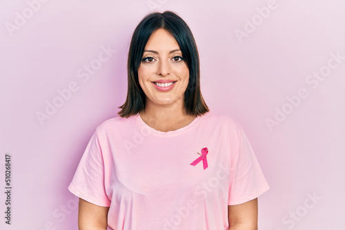 Young hispanic woman wearing pink cancer ribbon on t shirt with a happy and cool smile on face. lucky person.